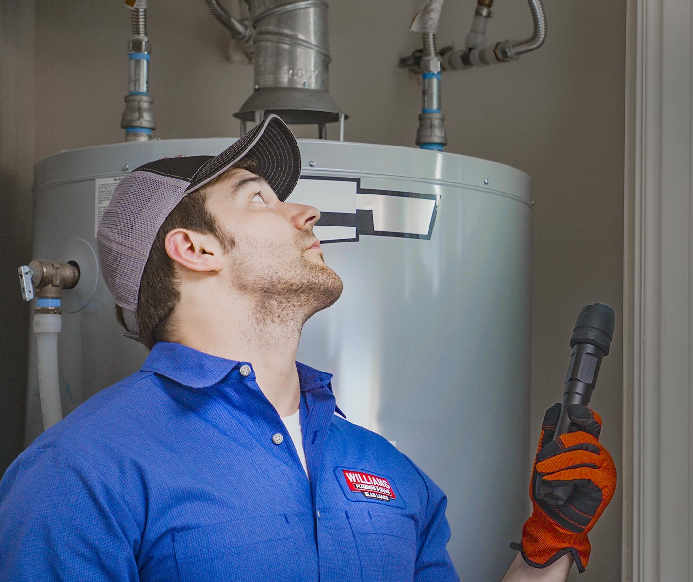 Williams Plumbing plumber inspecting a water heater.